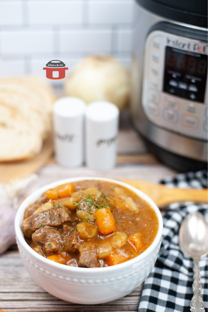 instant pot beef stew in white bowl sitting beside an instant pot
