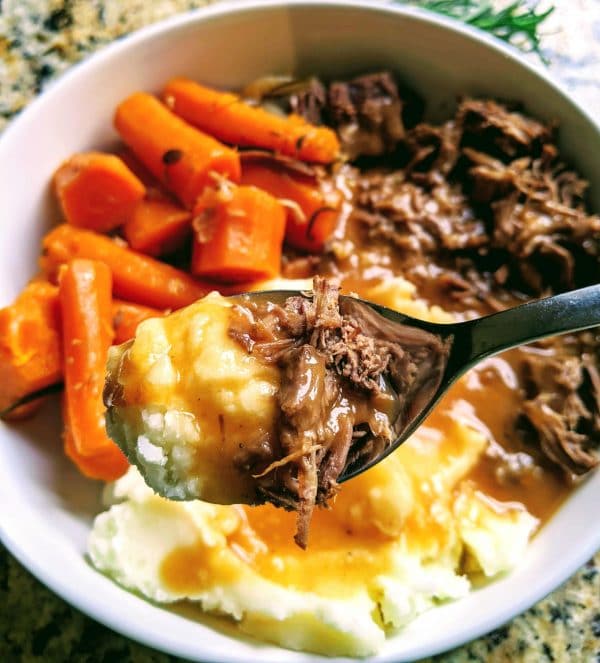 spoonful of pot roast and mashed potatoes over a bowl of the full meal